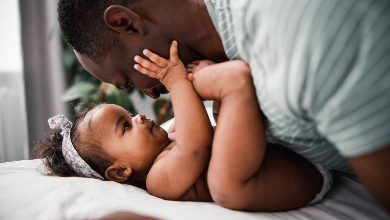 An African American baby girl playing with her dad.